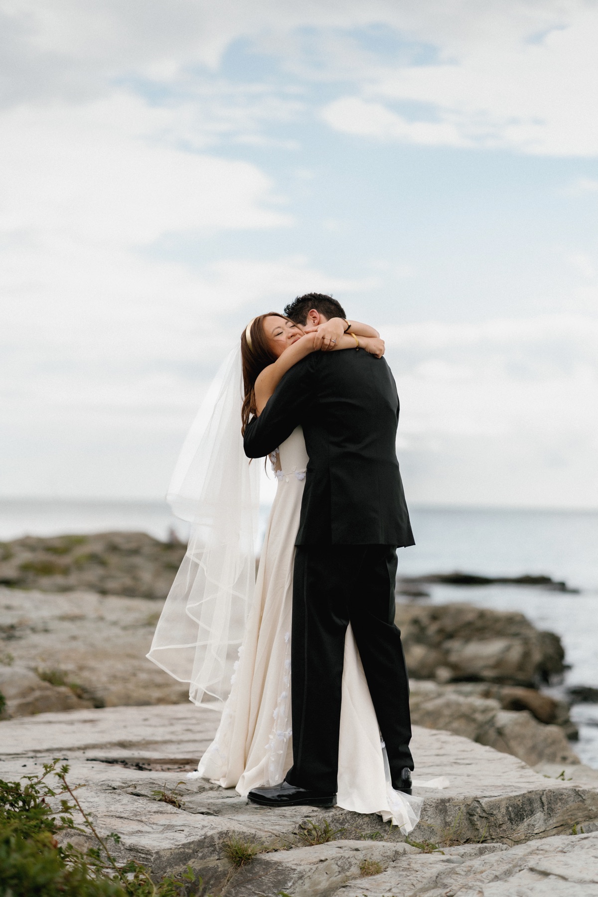 Michelle and Ralph hugging on the rocks by the ocean